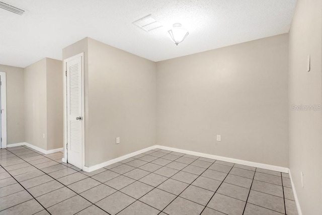 tiled empty room featuring a textured ceiling