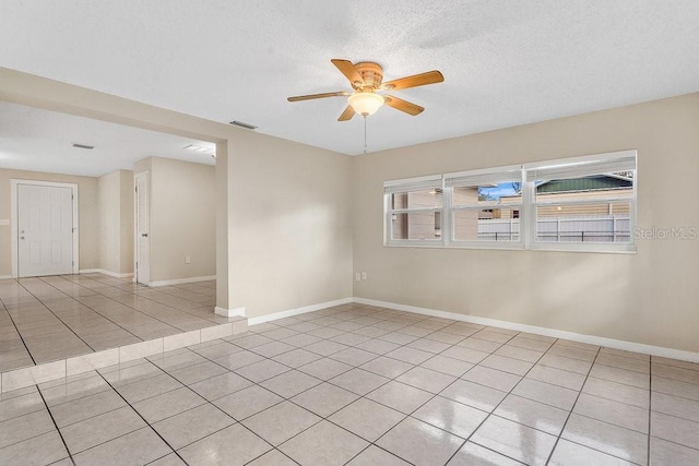 tiled spare room with ceiling fan, plenty of natural light, and a textured ceiling