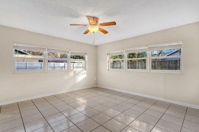 spare room with ceiling fan, light tile patterned floors, and a textured ceiling