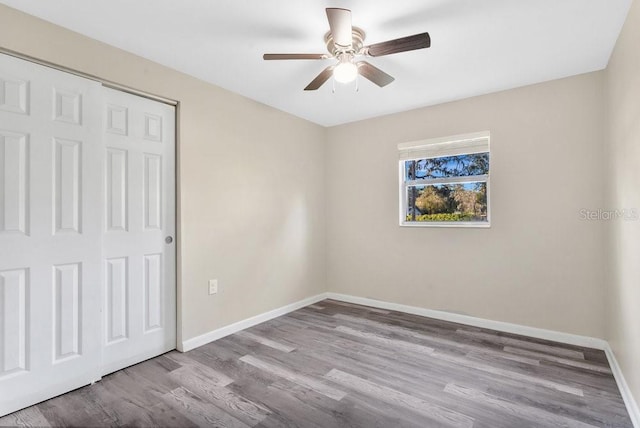 unfurnished bedroom featuring ceiling fan, a closet, and light wood-type flooring