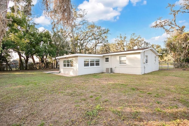 rear view of property with a lawn and cooling unit