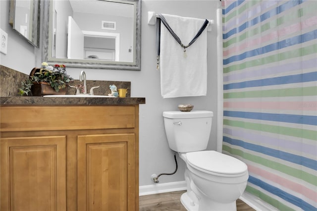 bathroom with wood-type flooring, vanity, toilet, and walk in shower