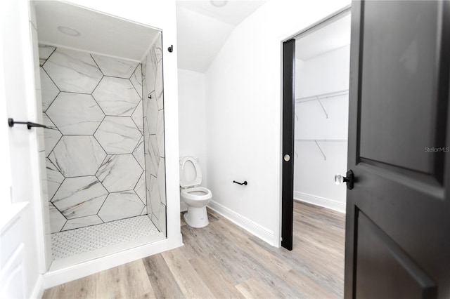 bathroom featuring hardwood / wood-style flooring, toilet, and tiled shower