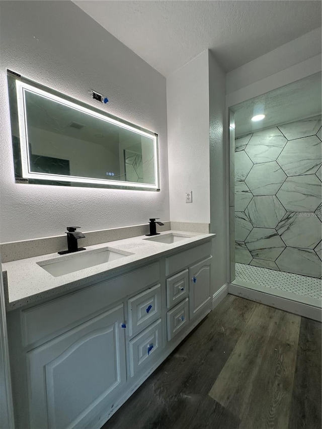 bathroom with hardwood / wood-style floors, vanity, a textured ceiling, and tiled shower