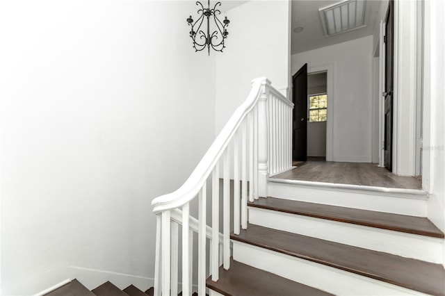 stairs featuring a notable chandelier