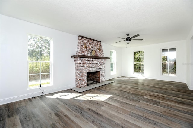 unfurnished living room featuring ceiling fan, wood-type flooring, a textured ceiling, and a brick fireplace