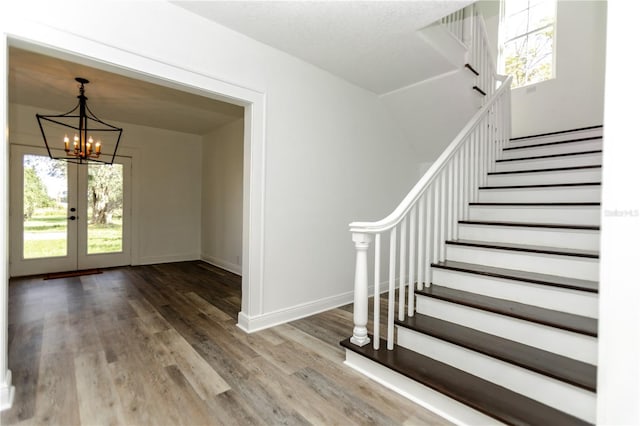 foyer entrance with french doors, a chandelier, and hardwood / wood-style flooring