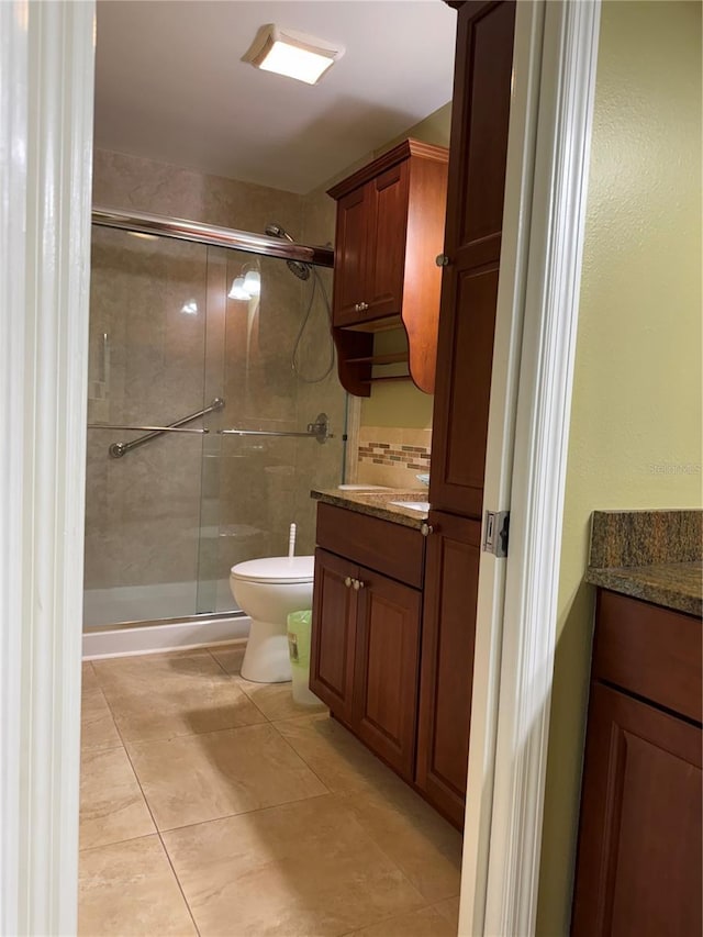 bathroom featuring tile patterned flooring, vanity, walk in shower, and toilet