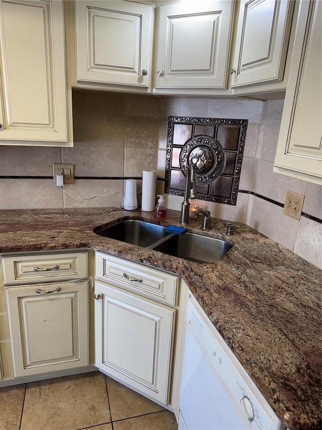 kitchen with dark stone counters, white dishwasher, sink, and decorative backsplash