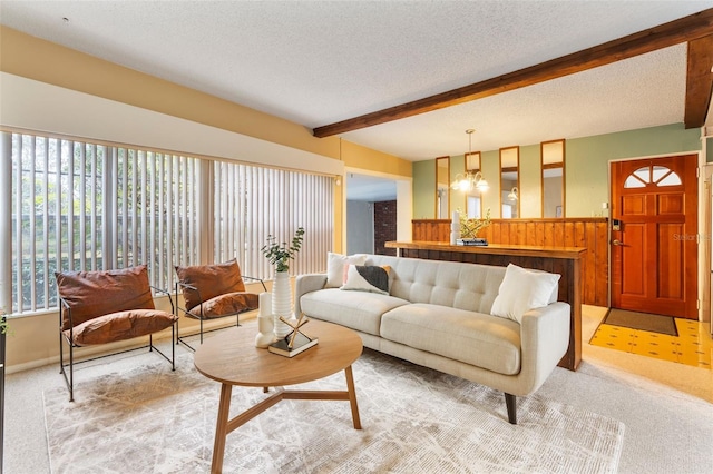 carpeted living room featuring a chandelier, a textured ceiling, and beamed ceiling