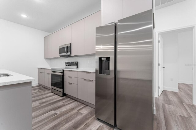 kitchen featuring gray cabinets, appliances with stainless steel finishes, and light hardwood / wood-style flooring