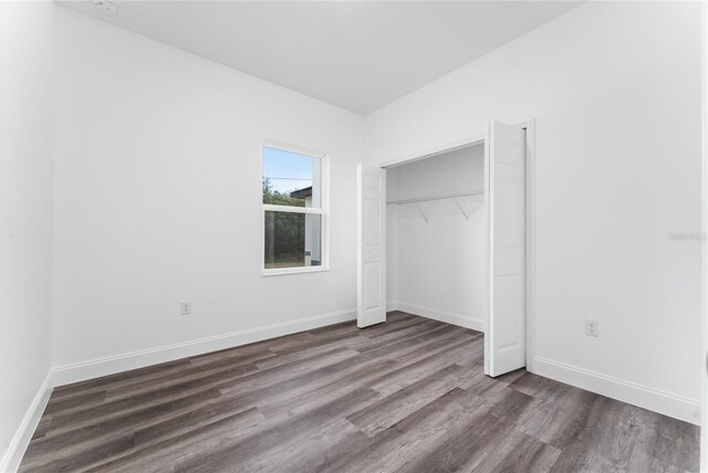 unfurnished bedroom with a closet and dark hardwood / wood-style floors