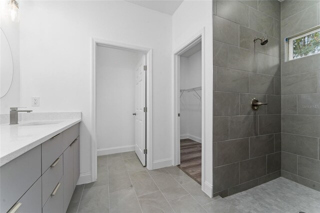 bathroom with tile patterned flooring, vanity, and a tile shower