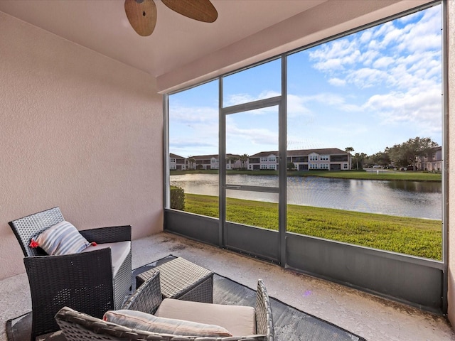 sunroom / solarium with ceiling fan and a water view