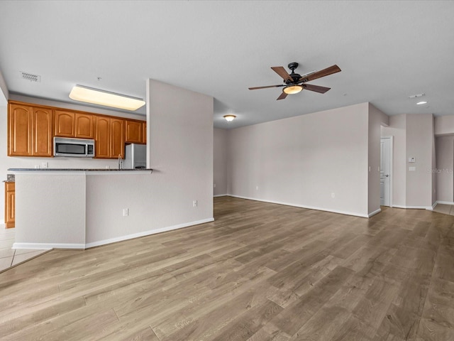 unfurnished living room featuring ceiling fan and light wood-type flooring