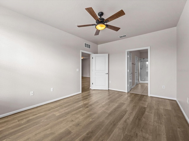 unfurnished bedroom featuring hardwood / wood-style floors, ensuite bath, and ceiling fan