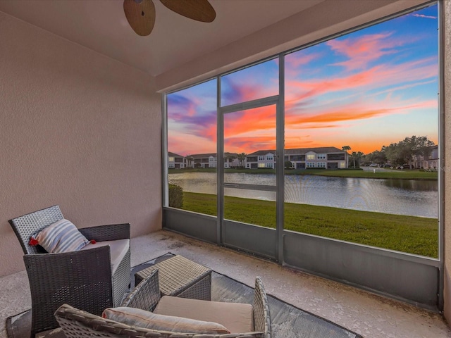 sunroom / solarium with ceiling fan and a water view