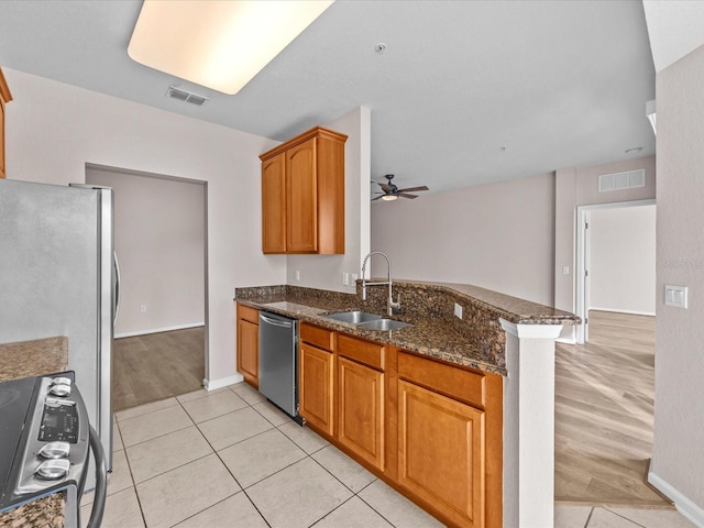 kitchen featuring sink, ceiling fan, dark stone countertops, stainless steel appliances, and kitchen peninsula