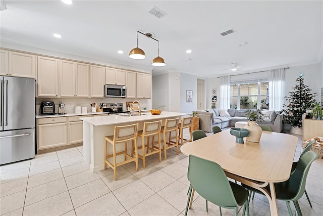 kitchen with pendant lighting, cream cabinetry, and appliances with stainless steel finishes