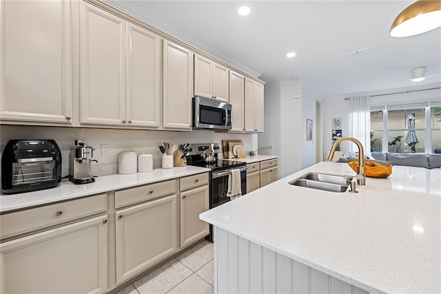 kitchen with cream cabinets, stainless steel appliances, light tile patterned floors, and sink