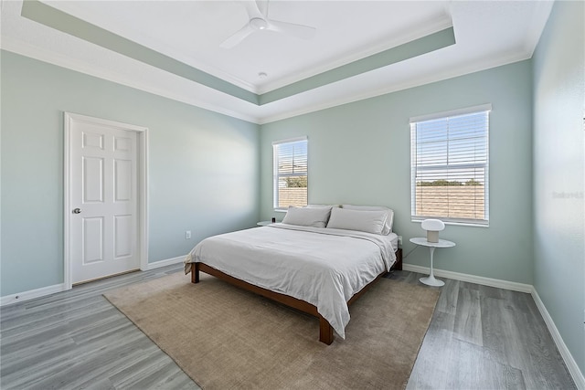 bedroom with a raised ceiling, ceiling fan, ornamental molding, and hardwood / wood-style flooring