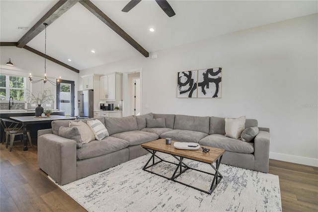 living room featuring sink, vaulted ceiling with beams, dark hardwood / wood-style flooring, and ceiling fan with notable chandelier