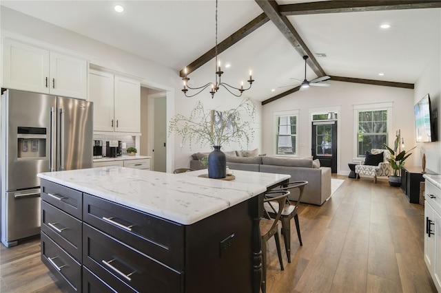 kitchen with a center island, white cabinets, lofted ceiling with beams, stainless steel fridge, and wood-type flooring