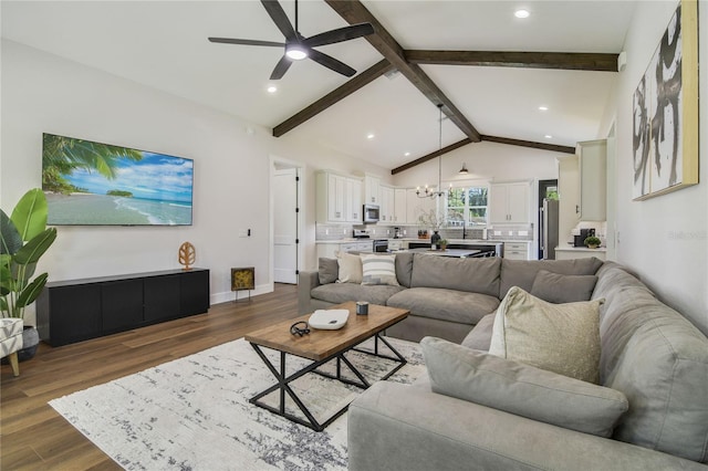 living room with lofted ceiling with beams, dark wood-type flooring, and ceiling fan with notable chandelier