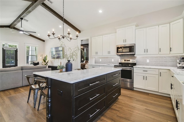 kitchen with lofted ceiling with beams, a center island, stainless steel appliances, and white cabinets