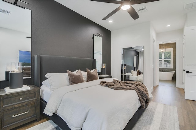 bedroom featuring ensuite bathroom, light hardwood / wood-style flooring, and ceiling fan