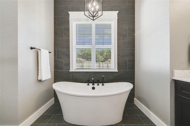 bathroom with a tub to relax in, tile patterned flooring, and vanity