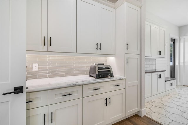 kitchen featuring tasteful backsplash, white cabinetry, dark wood-type flooring, and light stone counters