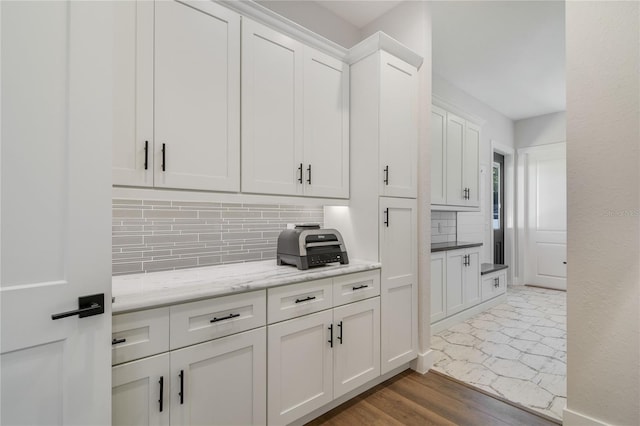 kitchen featuring backsplash, white cabinetry, light stone counters, and dark hardwood / wood-style floors