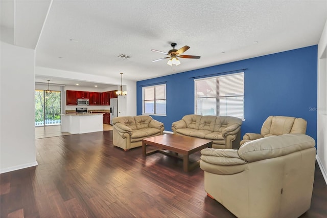 living room featuring ceiling fan, dark hardwood / wood-style flooring, and a textured ceiling