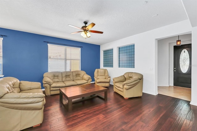 living room featuring dark hardwood / wood-style flooring, a textured ceiling, and ceiling fan