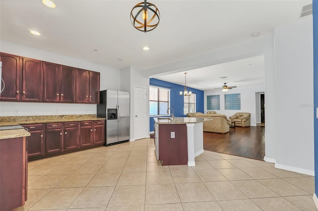 kitchen with decorative light fixtures, light stone counters, light tile patterned flooring, ceiling fan with notable chandelier, and stainless steel fridge with ice dispenser