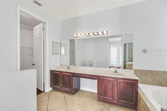 bathroom with toilet, tile patterned floors, tiled tub, and vanity