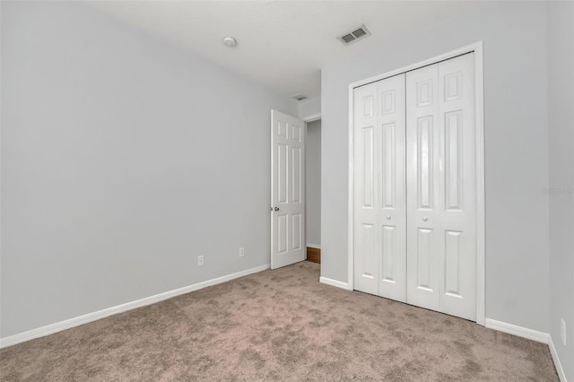 unfurnished bedroom featuring light colored carpet and a closet