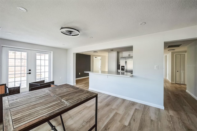 kitchen featuring kitchen peninsula, french doors, stainless steel fridge with ice dispenser, light hardwood / wood-style floors, and white cabinetry