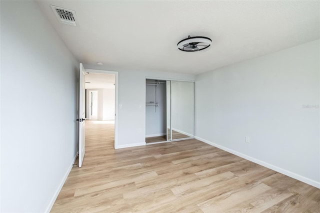 unfurnished bedroom featuring light hardwood / wood-style flooring and a closet