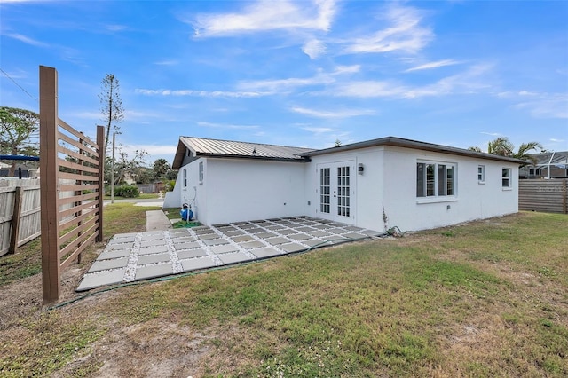 rear view of house featuring french doors, a patio, and a lawn