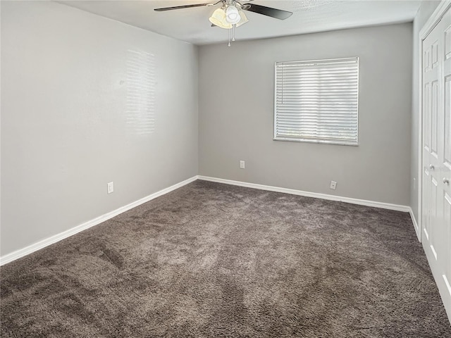 unfurnished bedroom featuring dark colored carpet, a closet, and ceiling fan