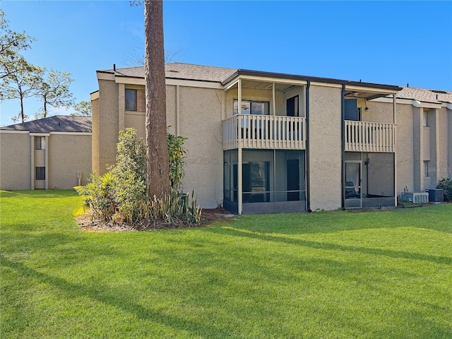 back of property with a yard, a balcony, and central air condition unit