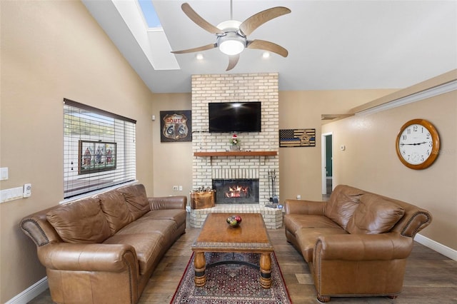 living room with a brick fireplace, dark hardwood / wood-style flooring, lofted ceiling with skylight, and ceiling fan