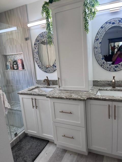 bathroom with hardwood / wood-style flooring, vanity, and a shower with door