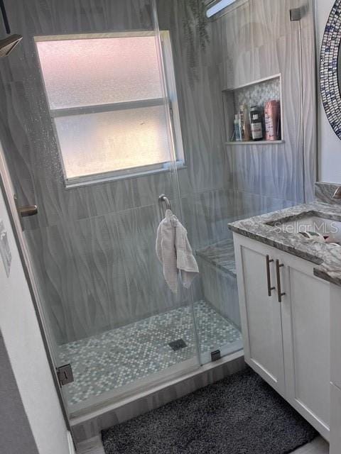 bathroom featuring vanity and a shower with door