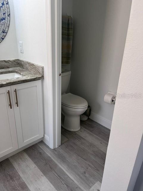 bathroom with hardwood / wood-style floors, vanity, and toilet