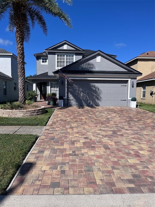 view of front of property with an attached garage, decorative driveway, and stucco siding