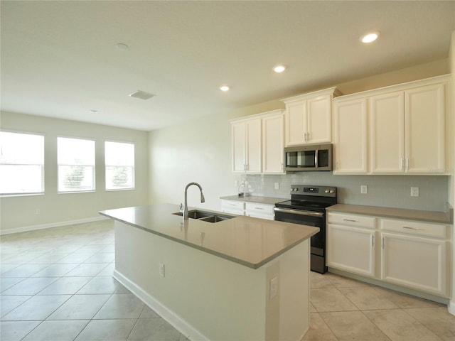 kitchen featuring electric range, sink, white cabinets, and an island with sink