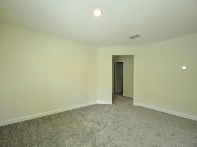 spare room featuring light carpet and a textured ceiling